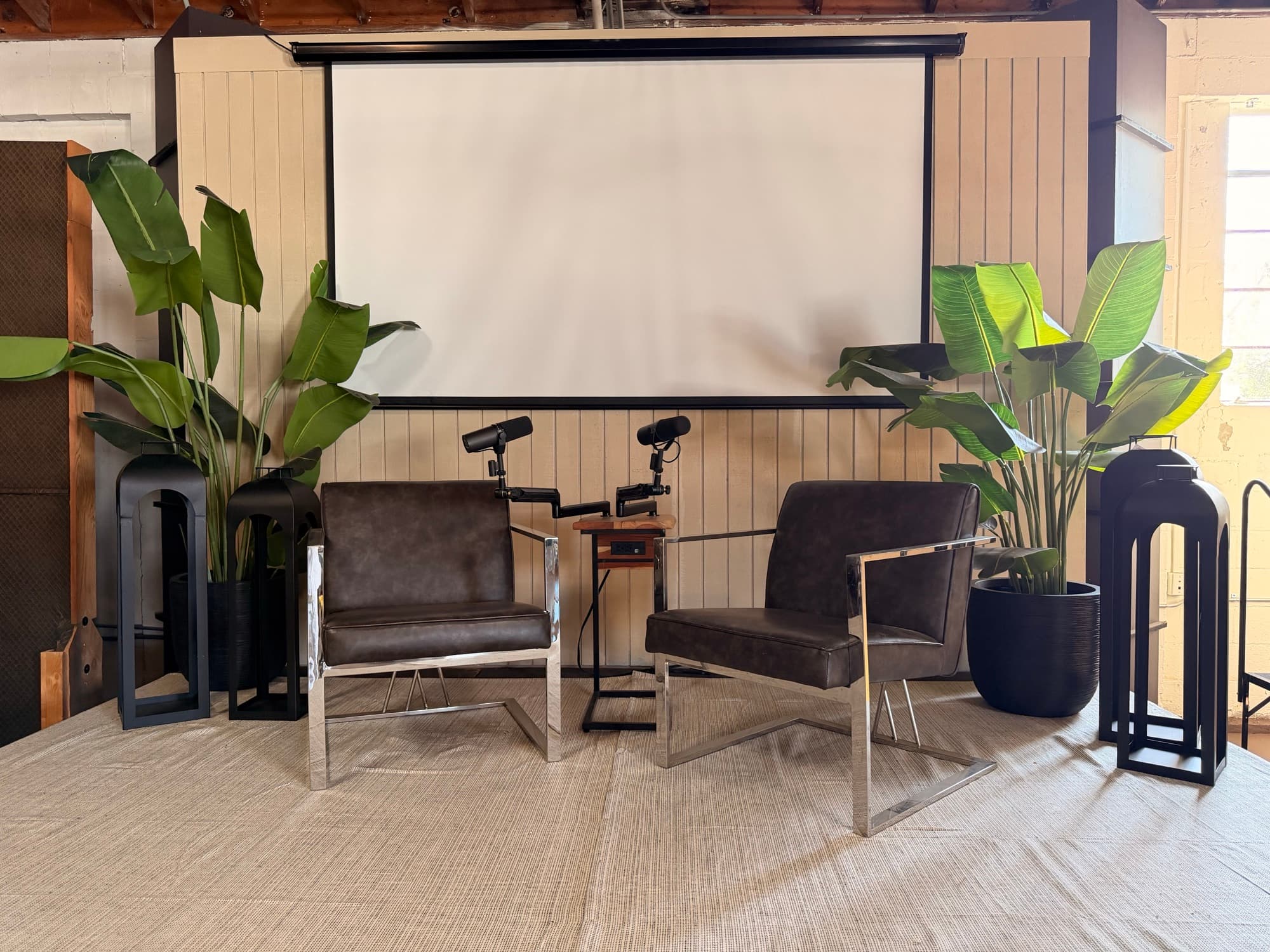 The podcast and interview set with two chairs facing each other and a projector screen