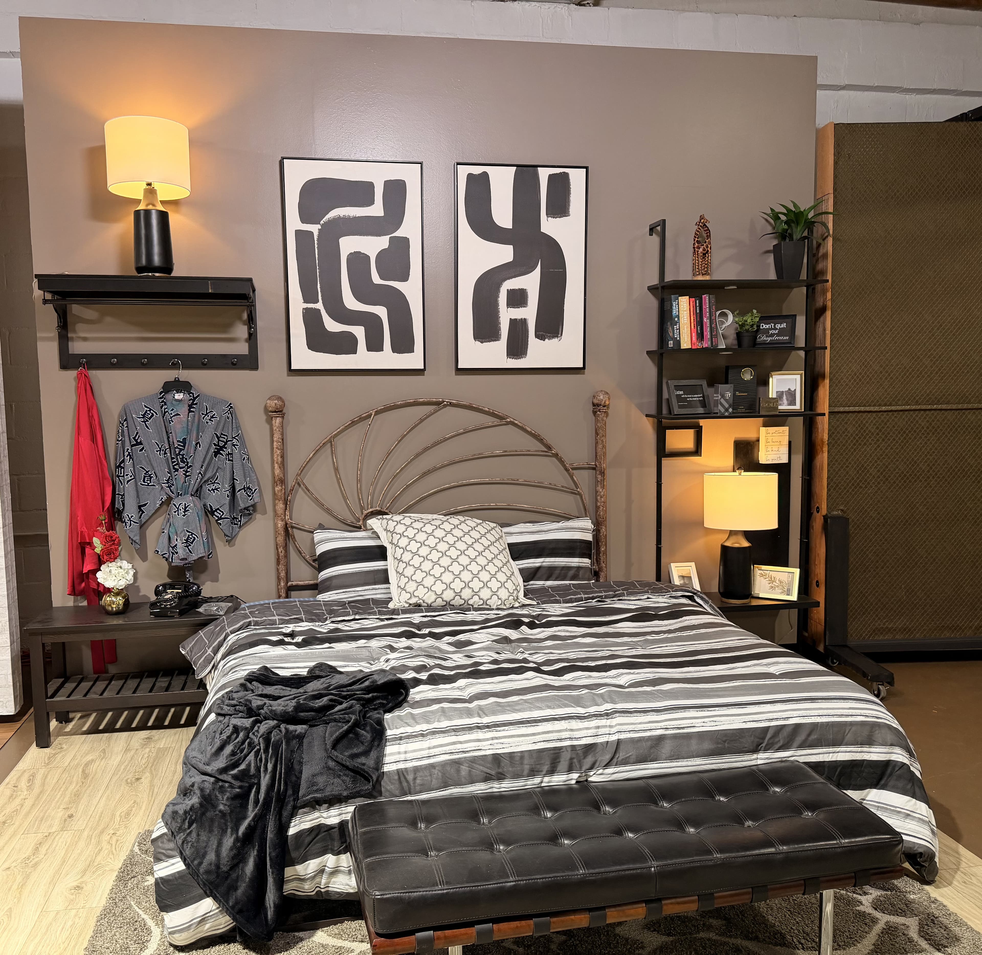 The bedroom standing set, fully dressed: iron bed frame, styled bedding, and warm lighting